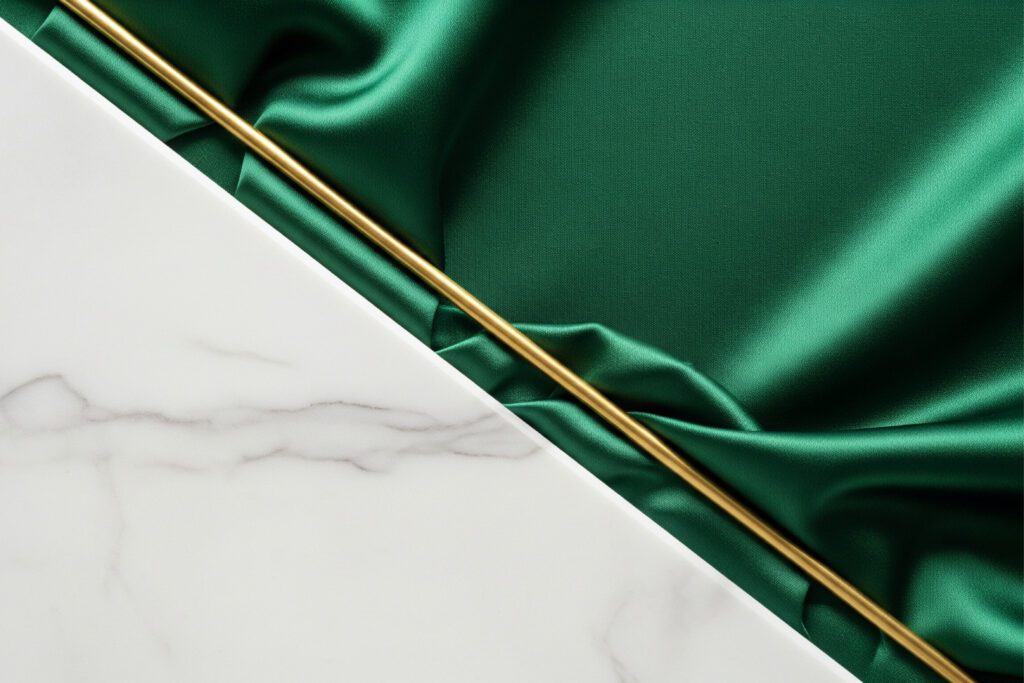 Elegáns anyagok és textúrák: fehér márvány, smaragdzöld selyem és egy vékony arany fémrúd letisztult kompozíciója a luxus design jegyében.